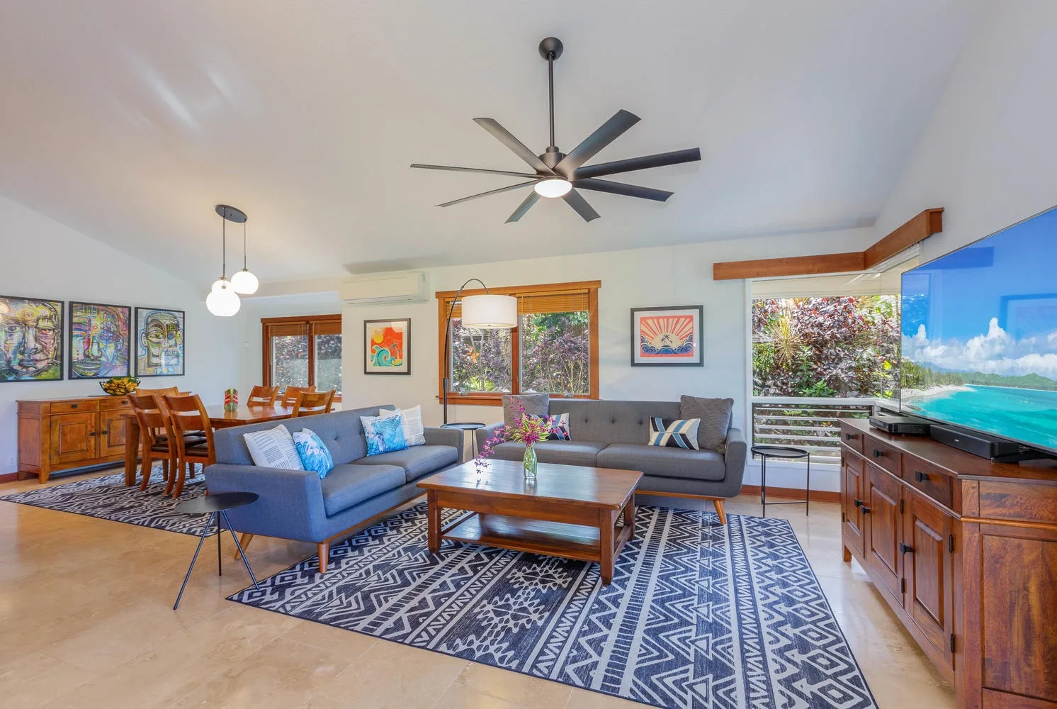 A bright living and dining area with seating, a dining table, and large windows.