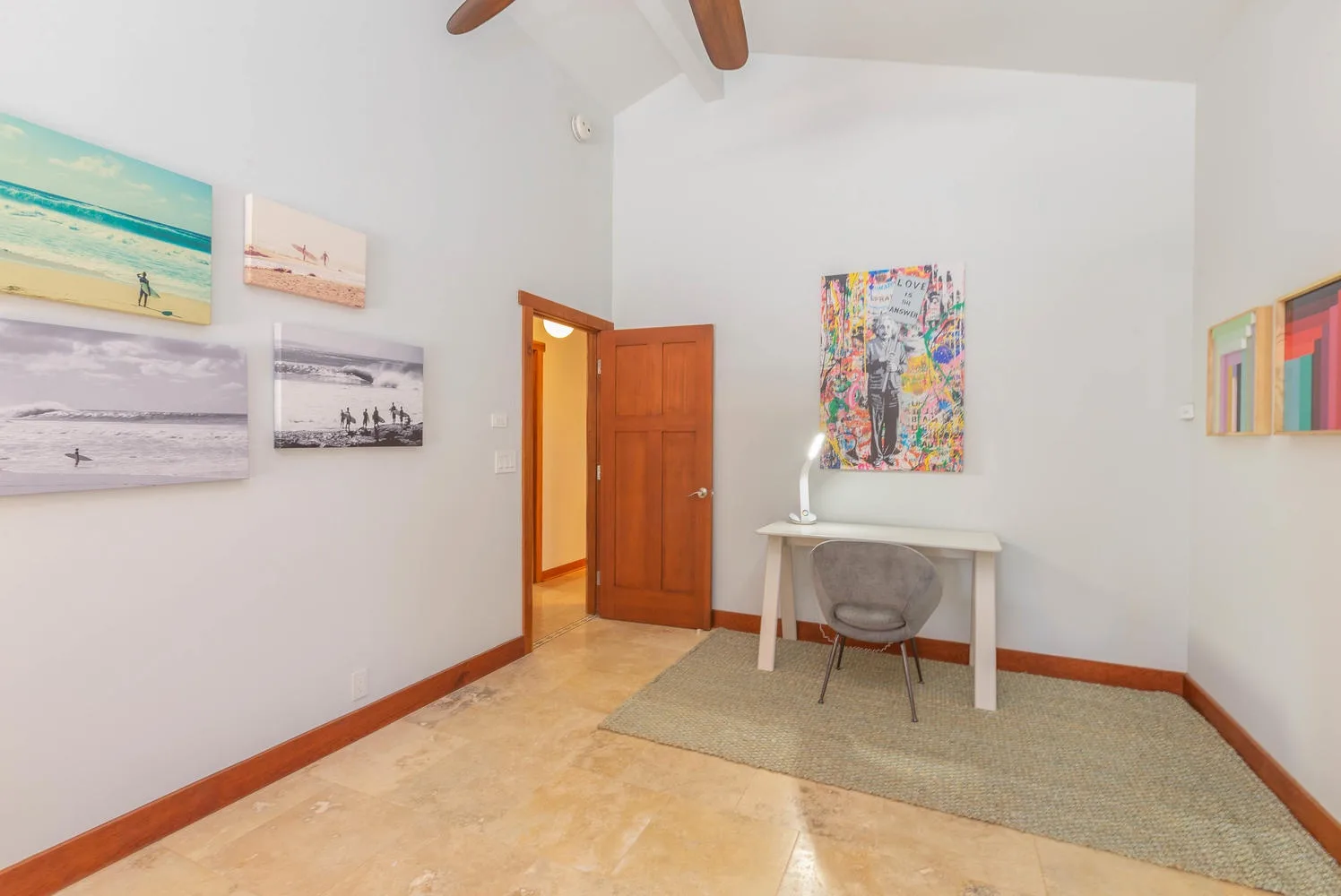 A bright room with a desk, chair, and colorful wall art.