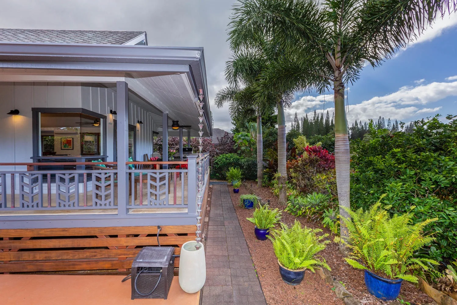 A covered outdoor patio beside a garden path lined with potted plants.