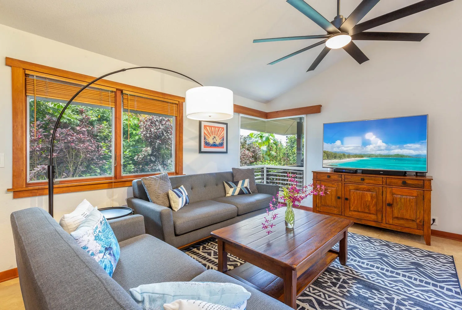 A bright living room with seating, a wooden coffee table, and large windows.