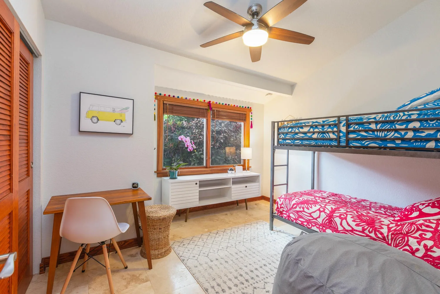 A bedroom with a loft bed, a desk, and a window.