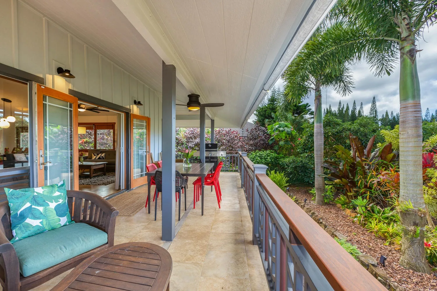 A covered outdoor patio with seating and a dining table overlooks a landscaped garden.