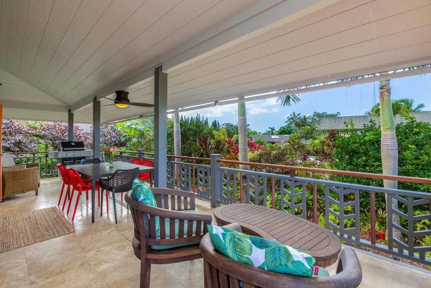 A covered outdoor patio has dining and seating areas overlooking a lush garden.
