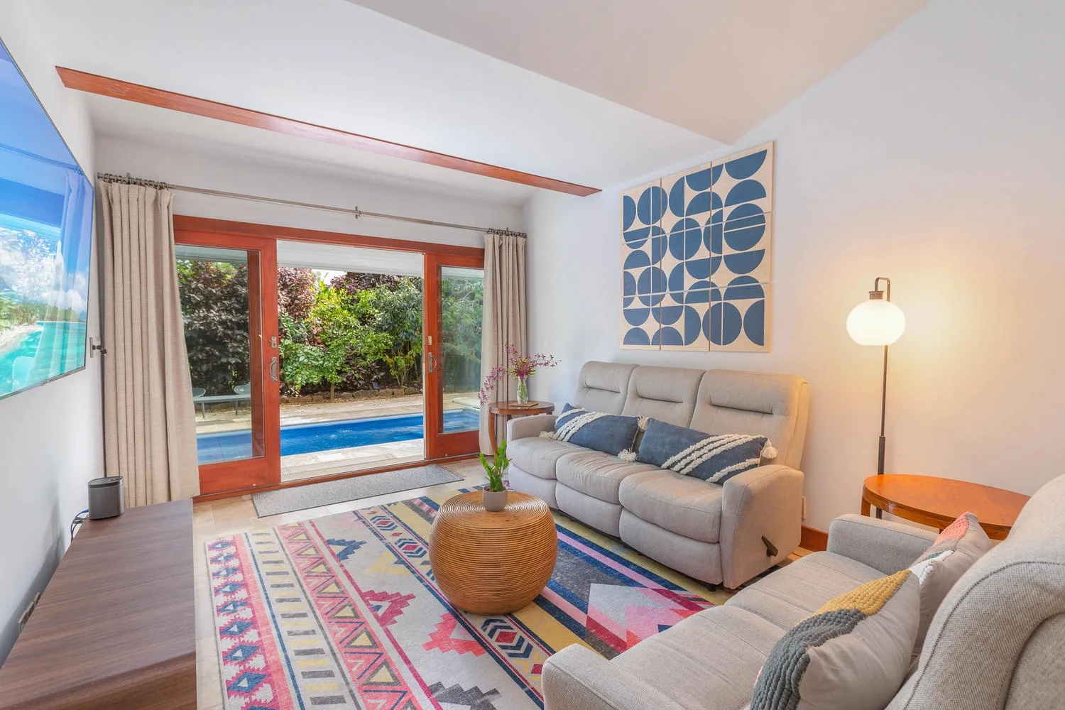 A bright living room with seating, a colorful rug, and large glass doors.