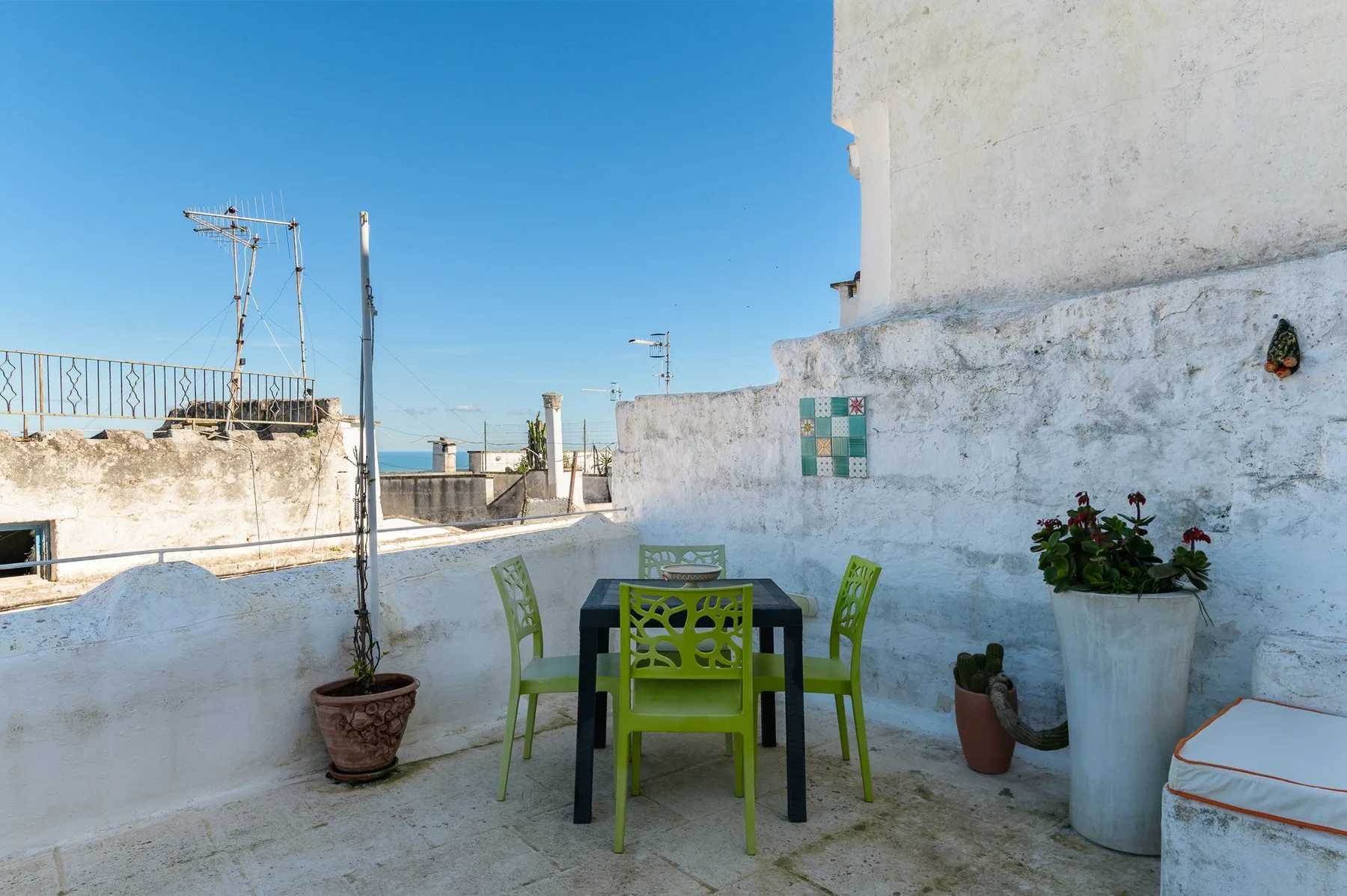 Una terraza en la azotea con asientos al aire libre, plantas en macetas y vistas al mar.