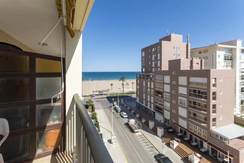 A balcony overlooks a street, nearby buildings, and the sea.