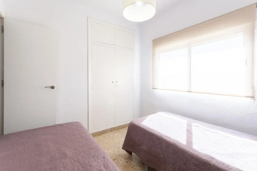 A bright bedroom with two beds and a large window.