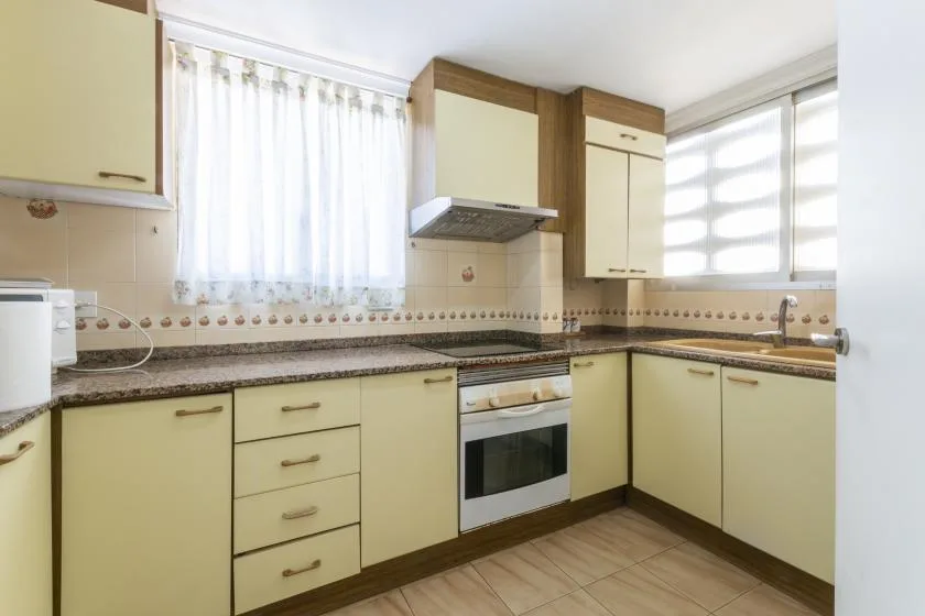 A bright kitchen with pale cabinets, a countertop, and a built-in oven.