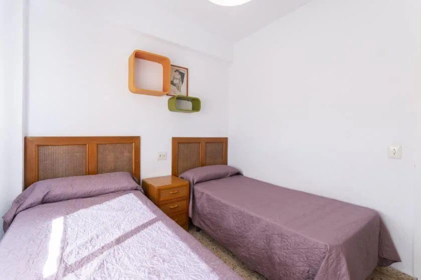 A bedroom with two beds and a small bedside table.