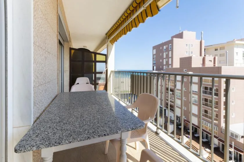 A balcony dining area with a stone table and neighboring buildings in view.