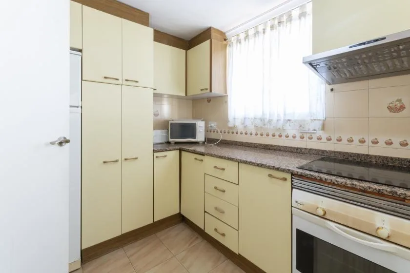 A bright kitchen with cream cabinets, a countertop, and a built-in oven.