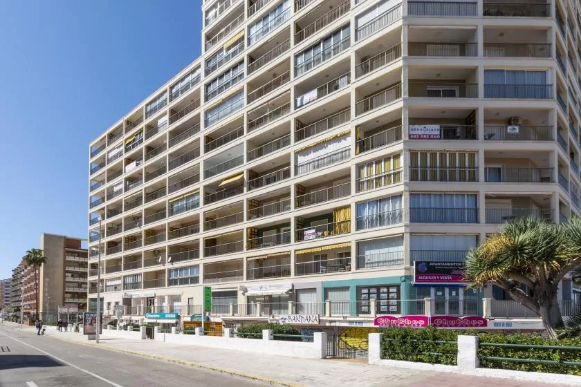 A high-rise apartment building with balconies along a street.