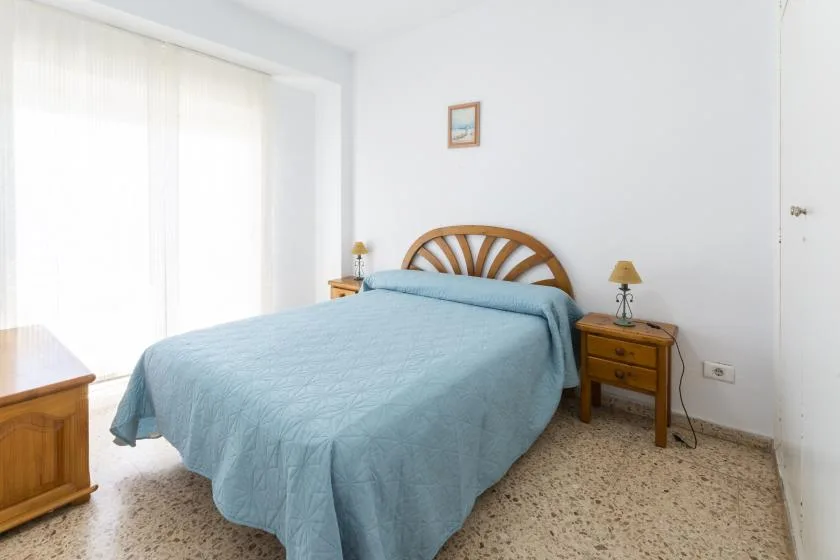 A bright bedroom with a bed covered in a blue bedspread.