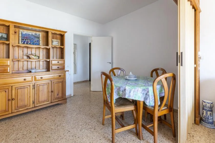 A dining area with a wooden table and chairs beside a large built-in cabinet.
