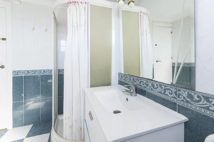 A bathroom with a white sink, mirror, and shower curtain.