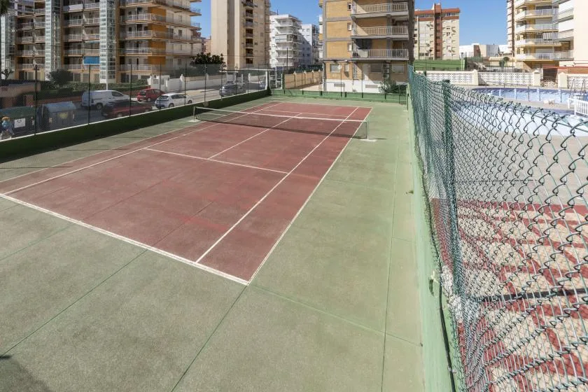 An outdoor tennis court with surrounding apartment buildings.
