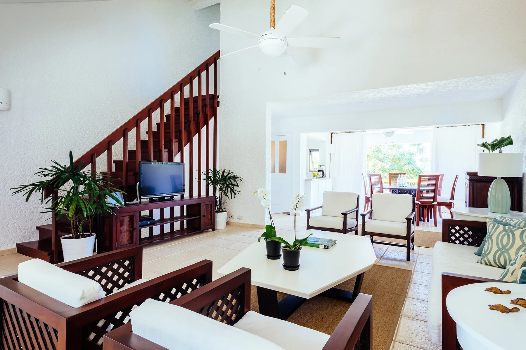 A living room with seating, a television, and a staircase.