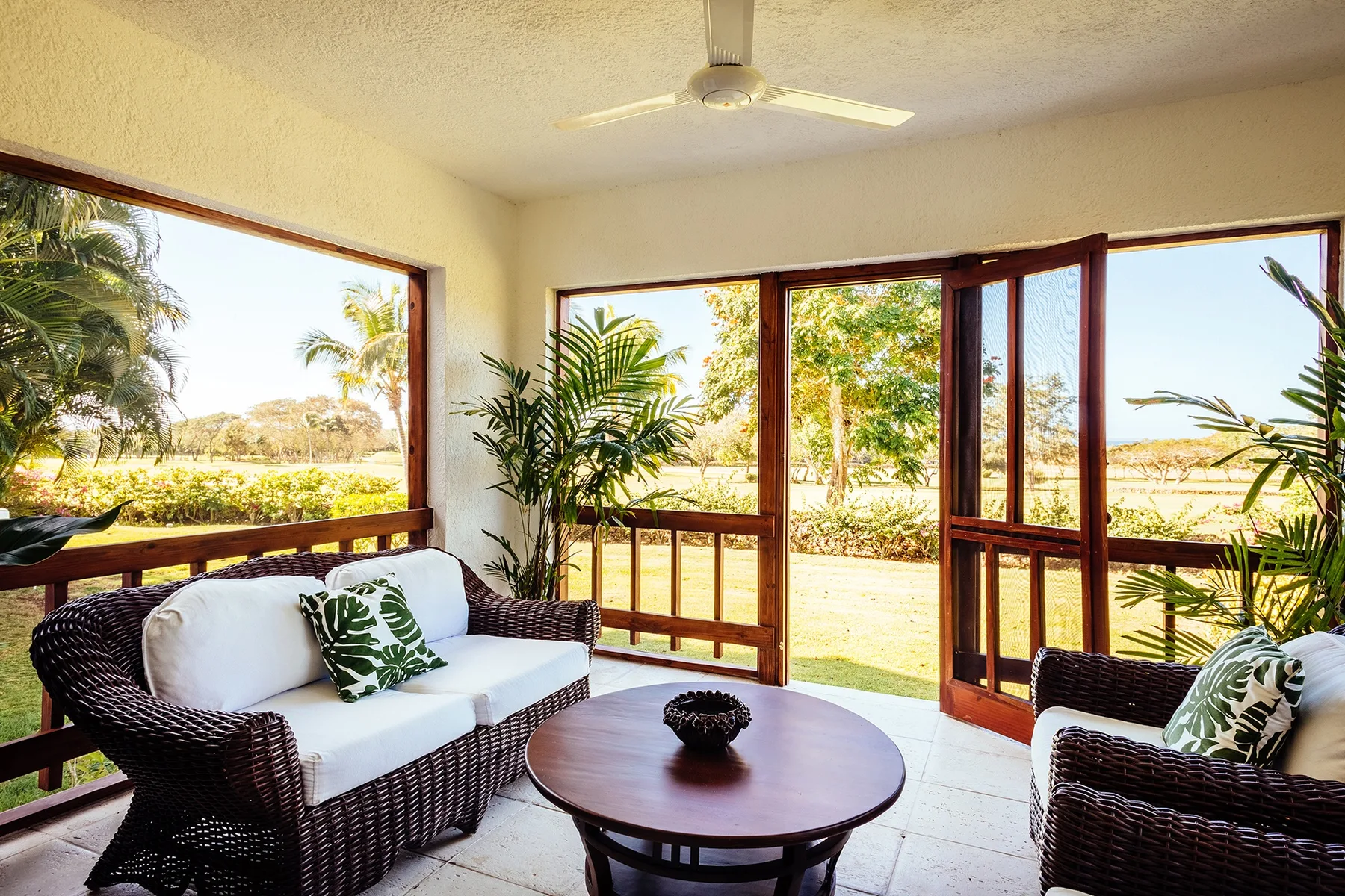 A bright sitting area opens onto a garden through wide windows and doors.