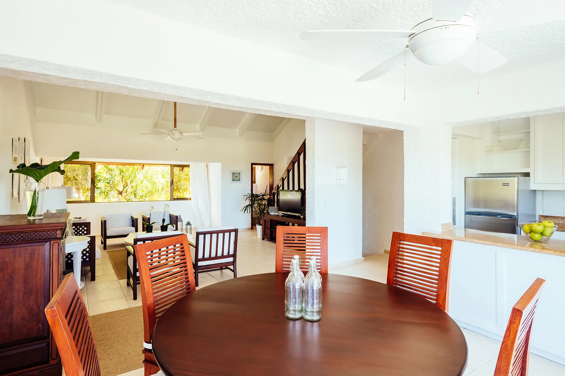 An open dining and kitchen area with a round table and wooden seating.