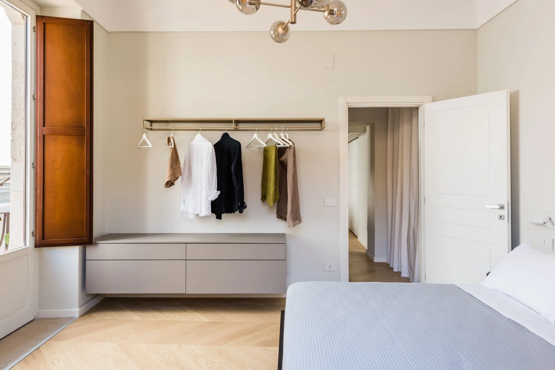 Un dormitorio con una cama y una barra de ropa en la pared.