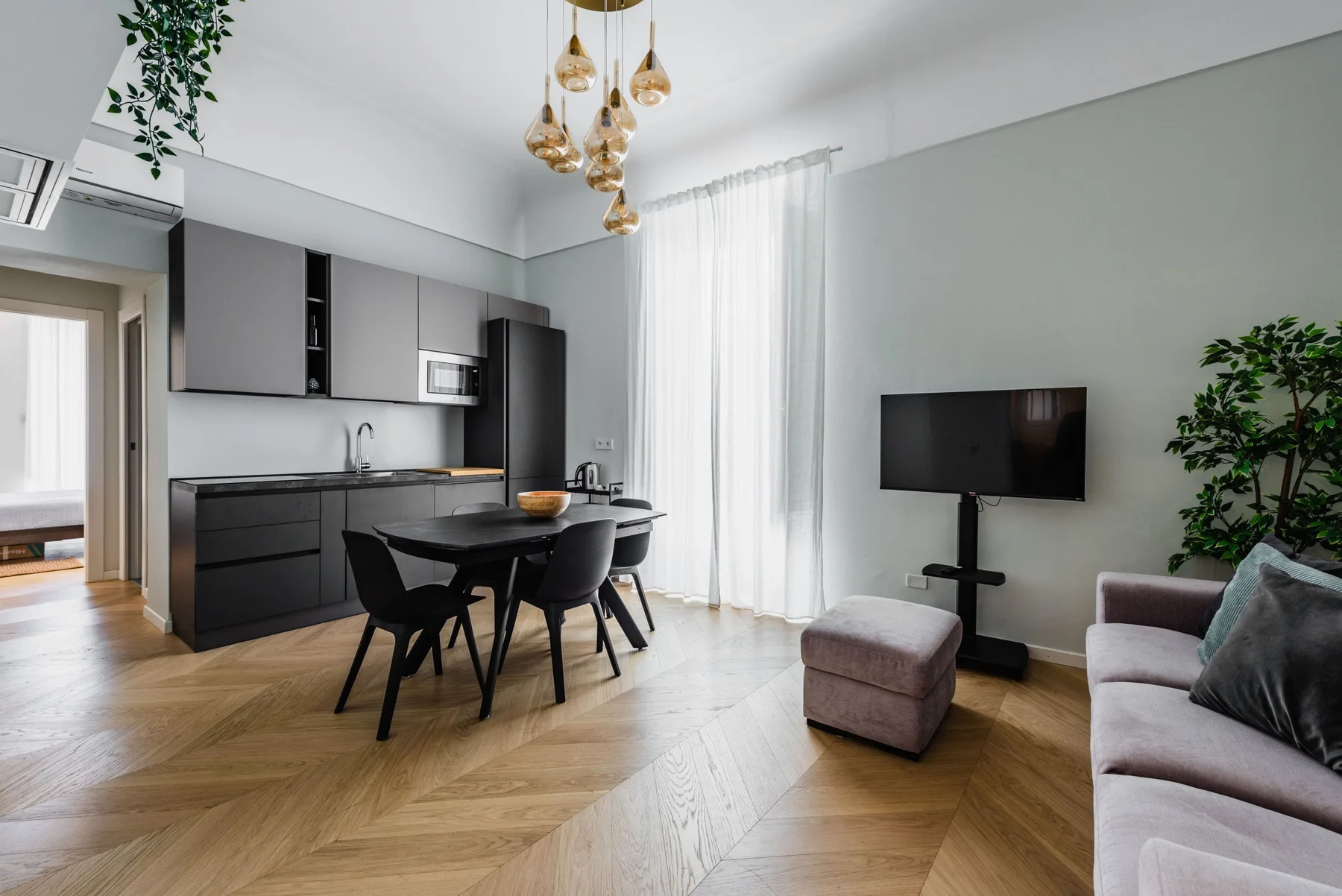 Una sala-comedor de estilo moderno con cocina, televisor y asientos.