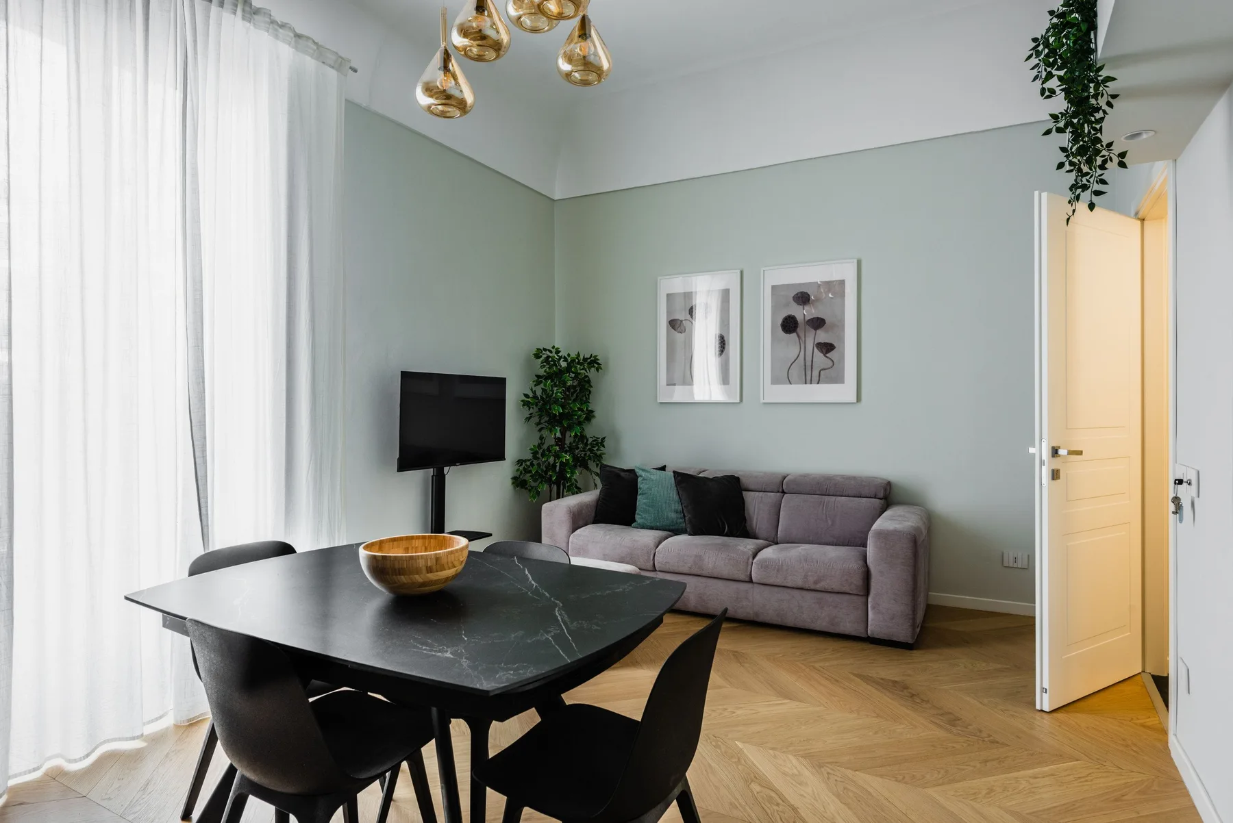 Una sala de estar y comedor con un sofá gris y una mesa de comedor oscura.