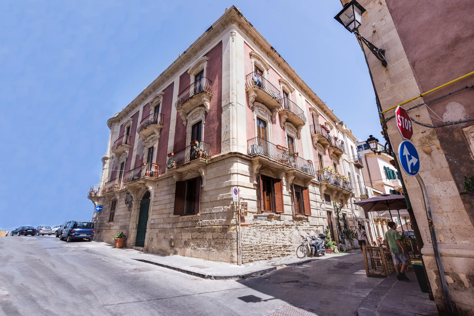 Esquina de una calle con un edificio antiguo de varias plantas, balcones y fachada de piedra.