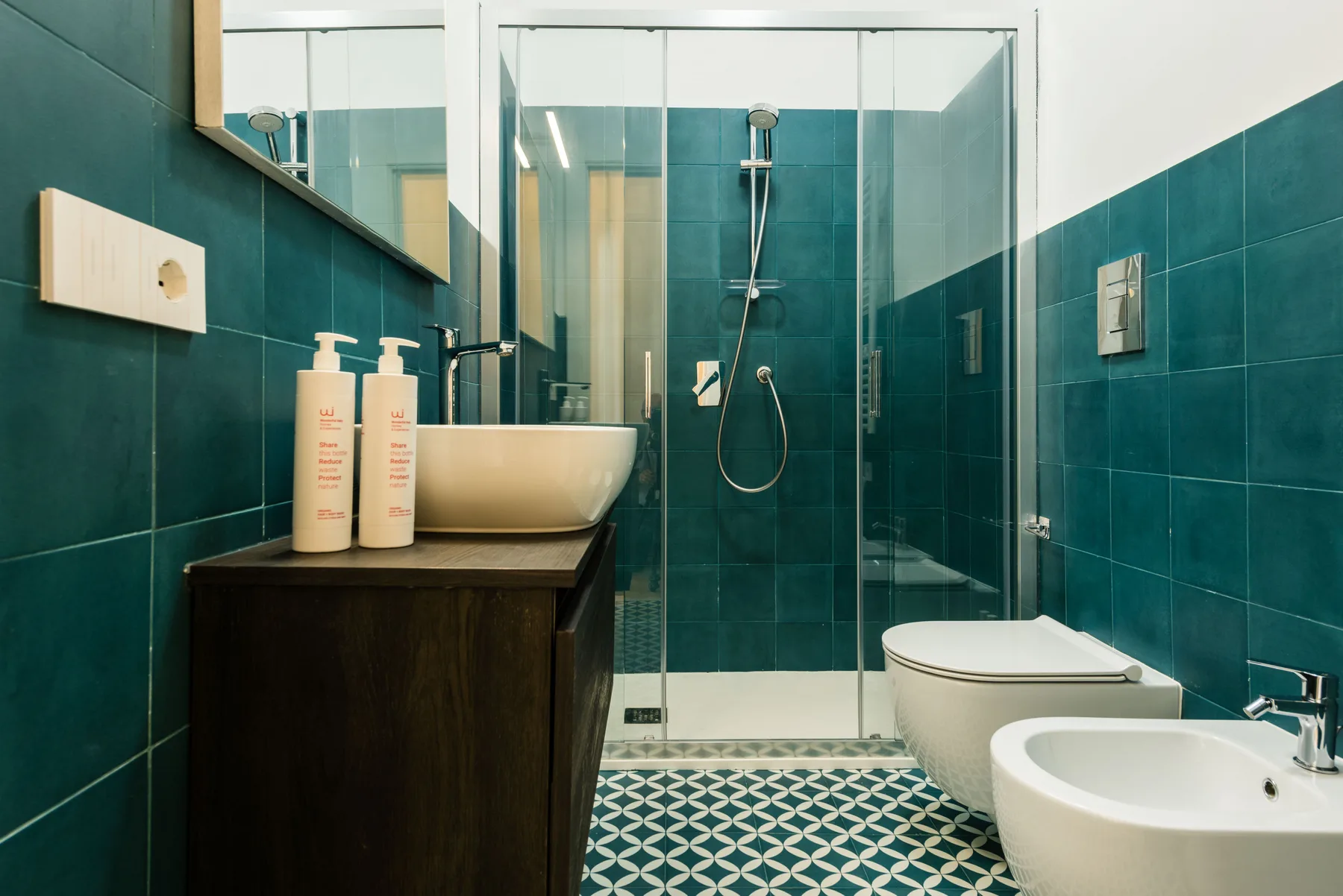 Un baño con azulejos, ducha de vidrio, lavabo e inodoro.