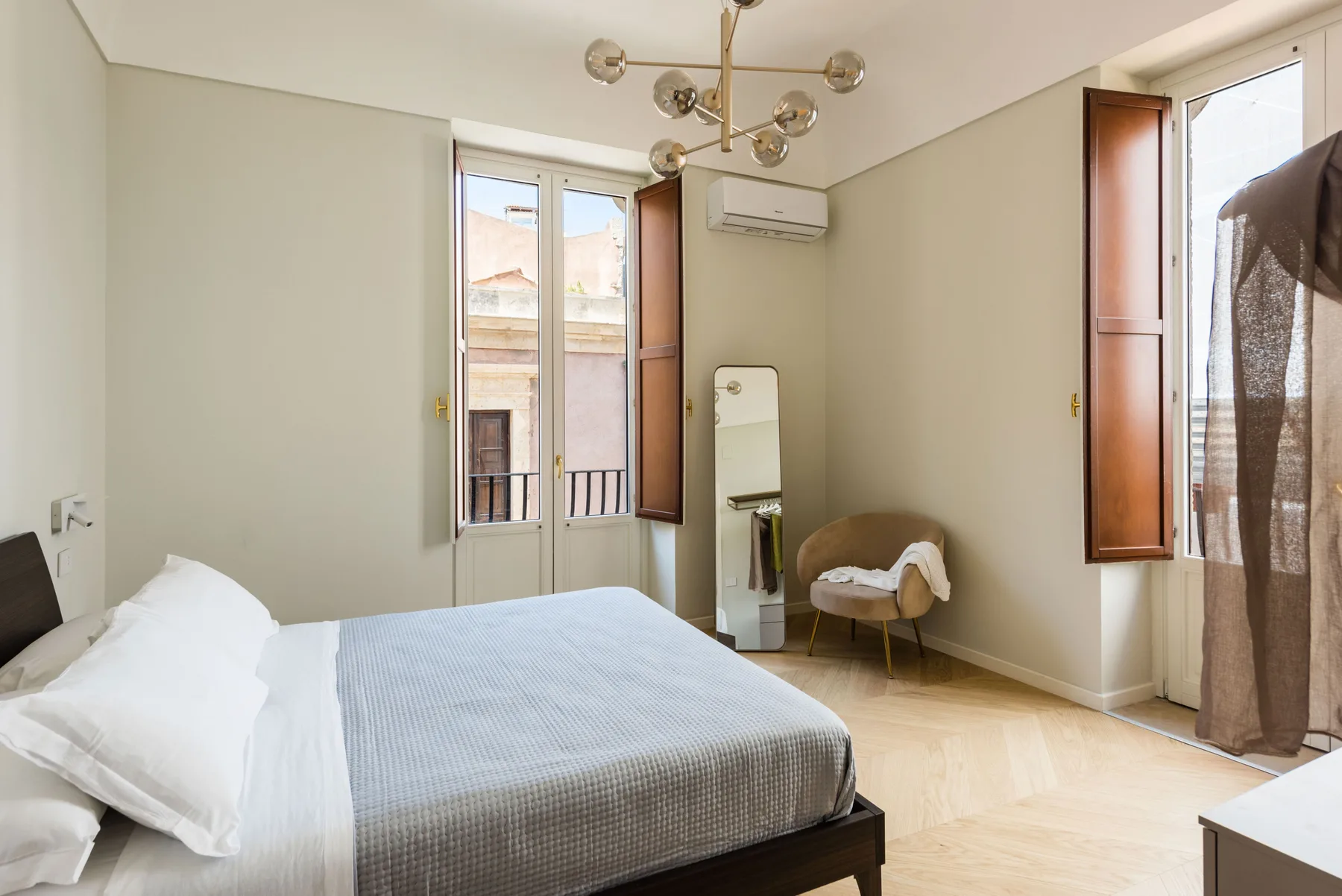 Un dormitorio luminoso con una cama grande y ventanas altas.