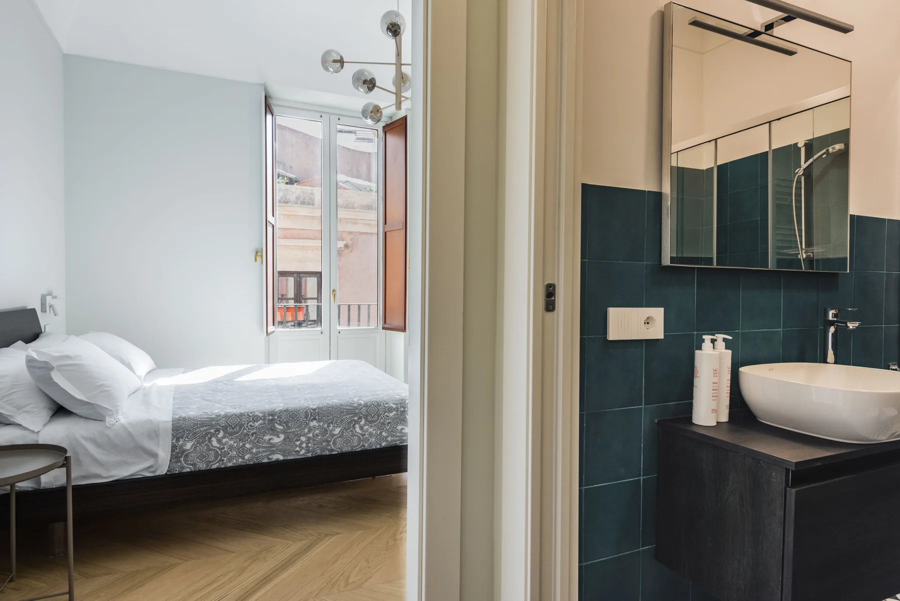Un dormitorio con una cama junto a un lavabo de baño y un espejo.