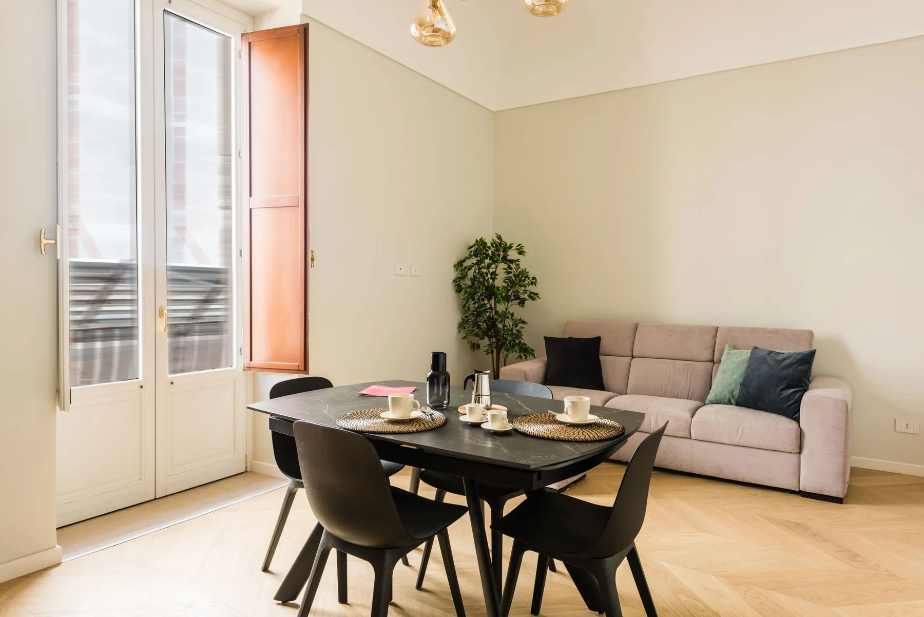Un comedor y zona de estar con una mesa, asientos y una planta en maceta.