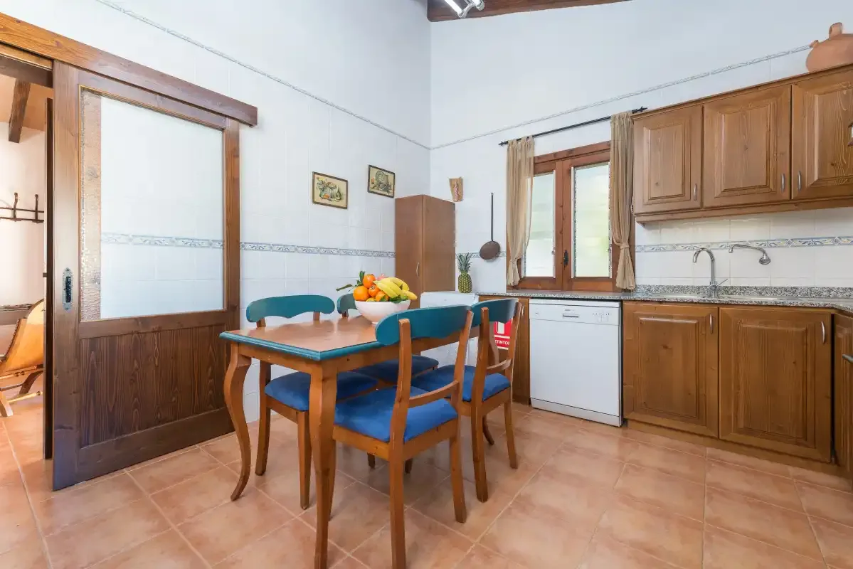A kitchen and dining area with wooden cabinets and a table beside the window.