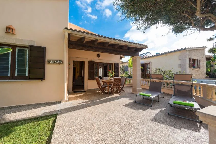 A sunny stone patio with outdoor seating, loungers, and a covered dining area.