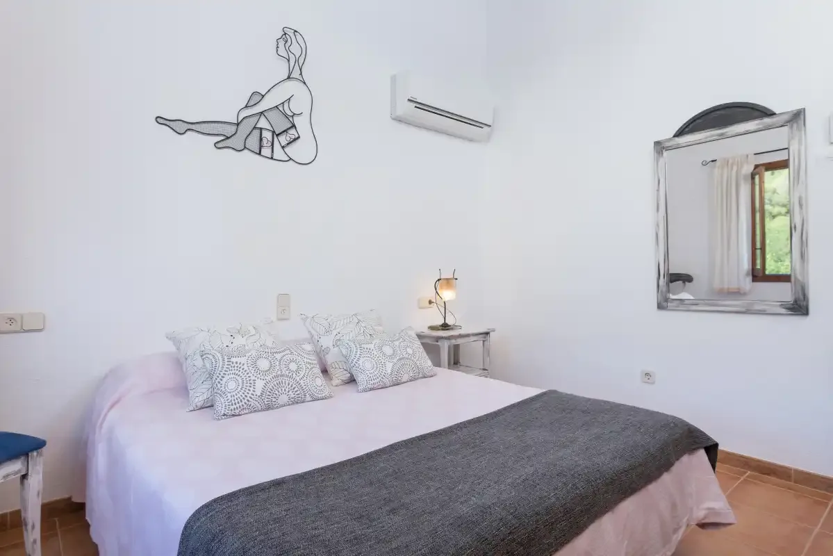 A bedroom with a bed, patterned pillows, and a bedside table.