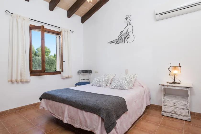 A bedroom with a bed beneath exposed wooden ceiling beams.