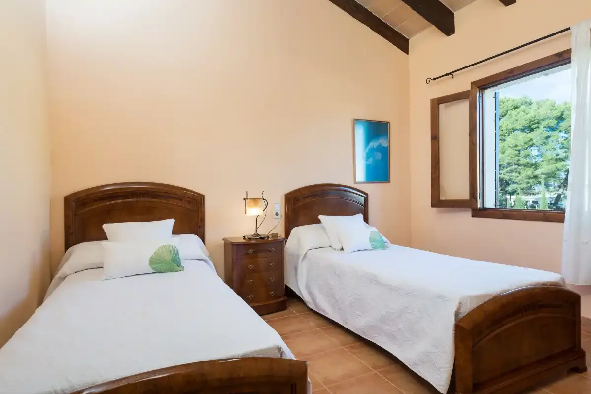 A bedroom with two single beds, bedside tables, and an open window.