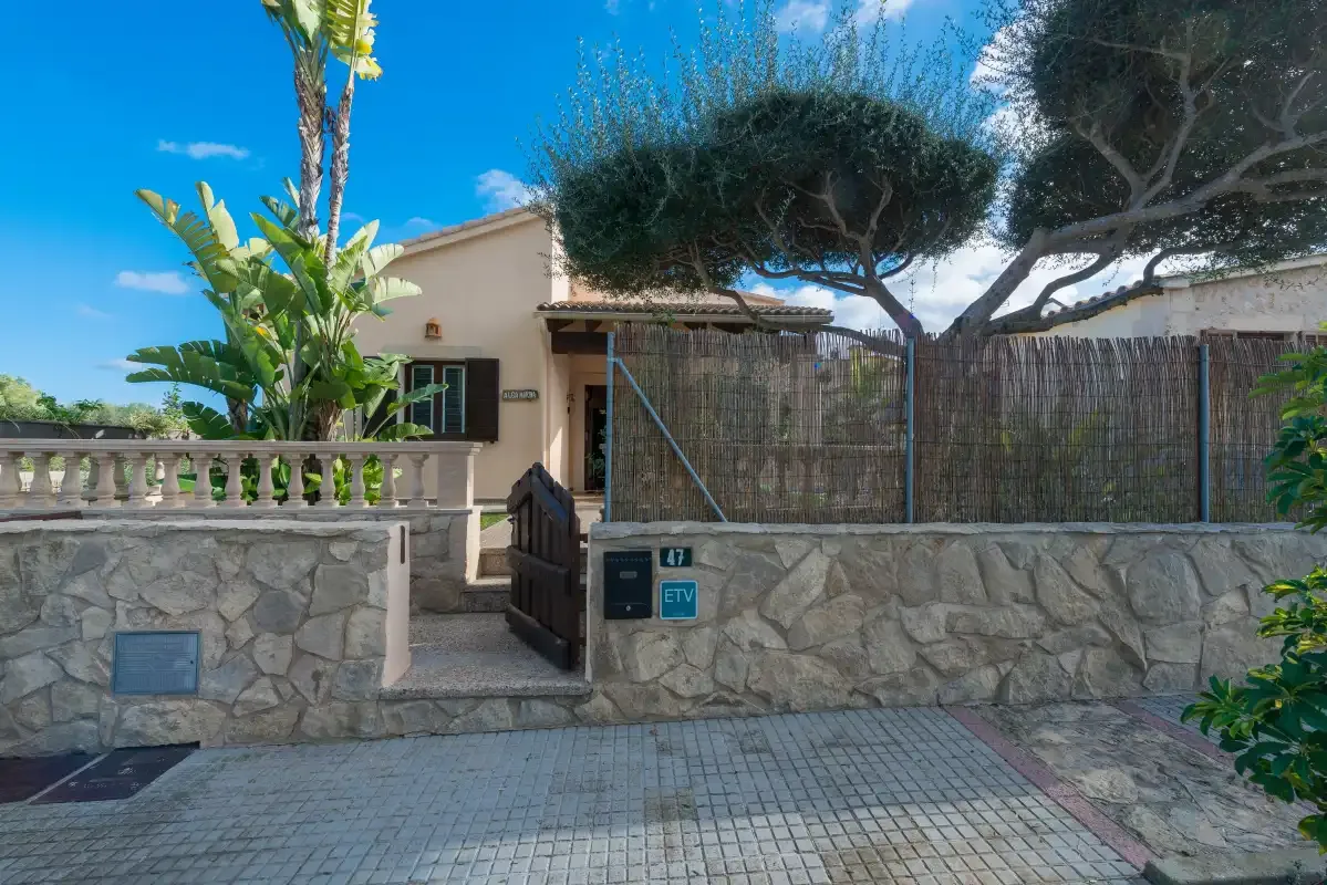 A house entrance sits behind a low stone wall and gate.