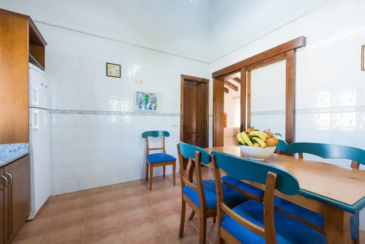 A tiled dining area with a wooden table and blue-seated chairs.