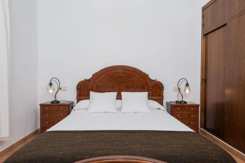 A bedroom with a bed, wooden headboard, and matching bedside tables.