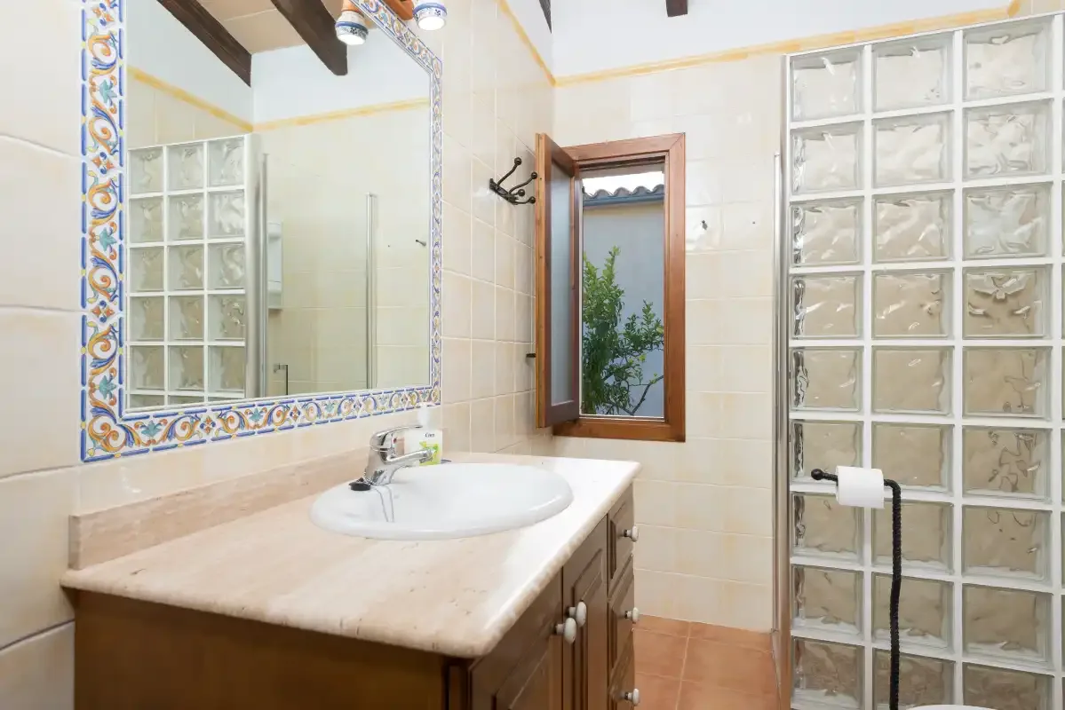 A bathroom with a sink, large mirror, and glass-block shower wall.