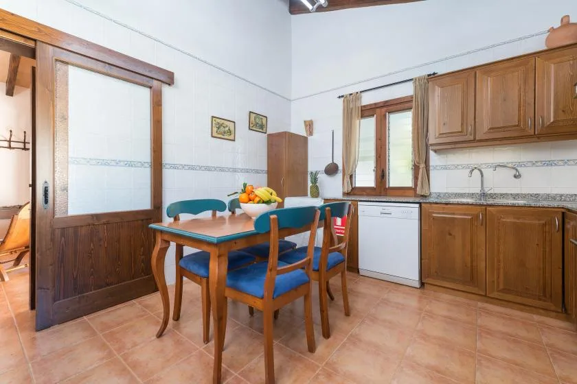 A kitchen dining area with a wooden table and blue seating beside the counter.