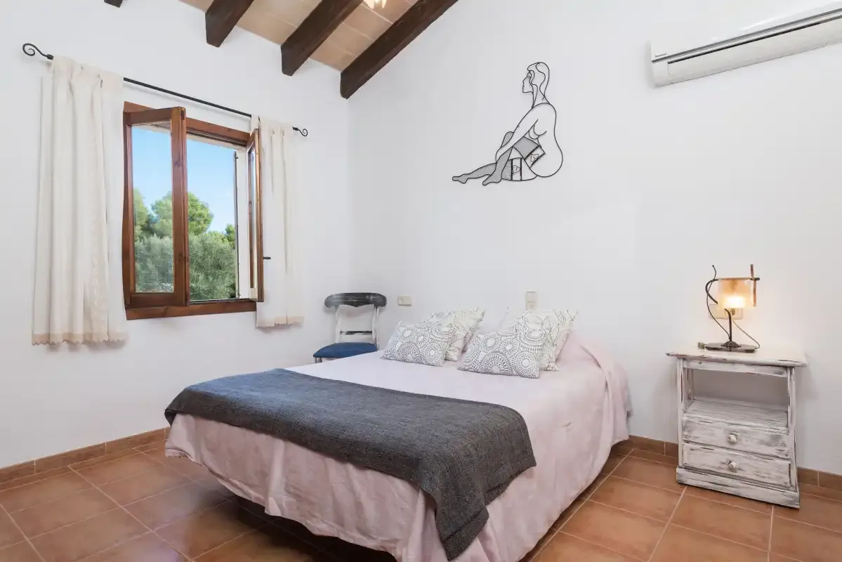 A bedroom with a bed, a window, and exposed ceiling beams.