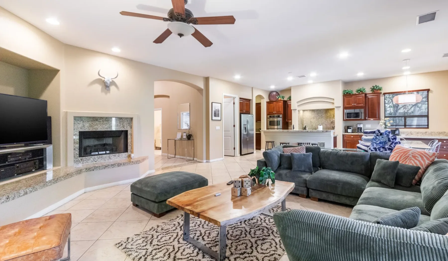 A living room with seating around a wooden coffee table and an open kitchen beyond.