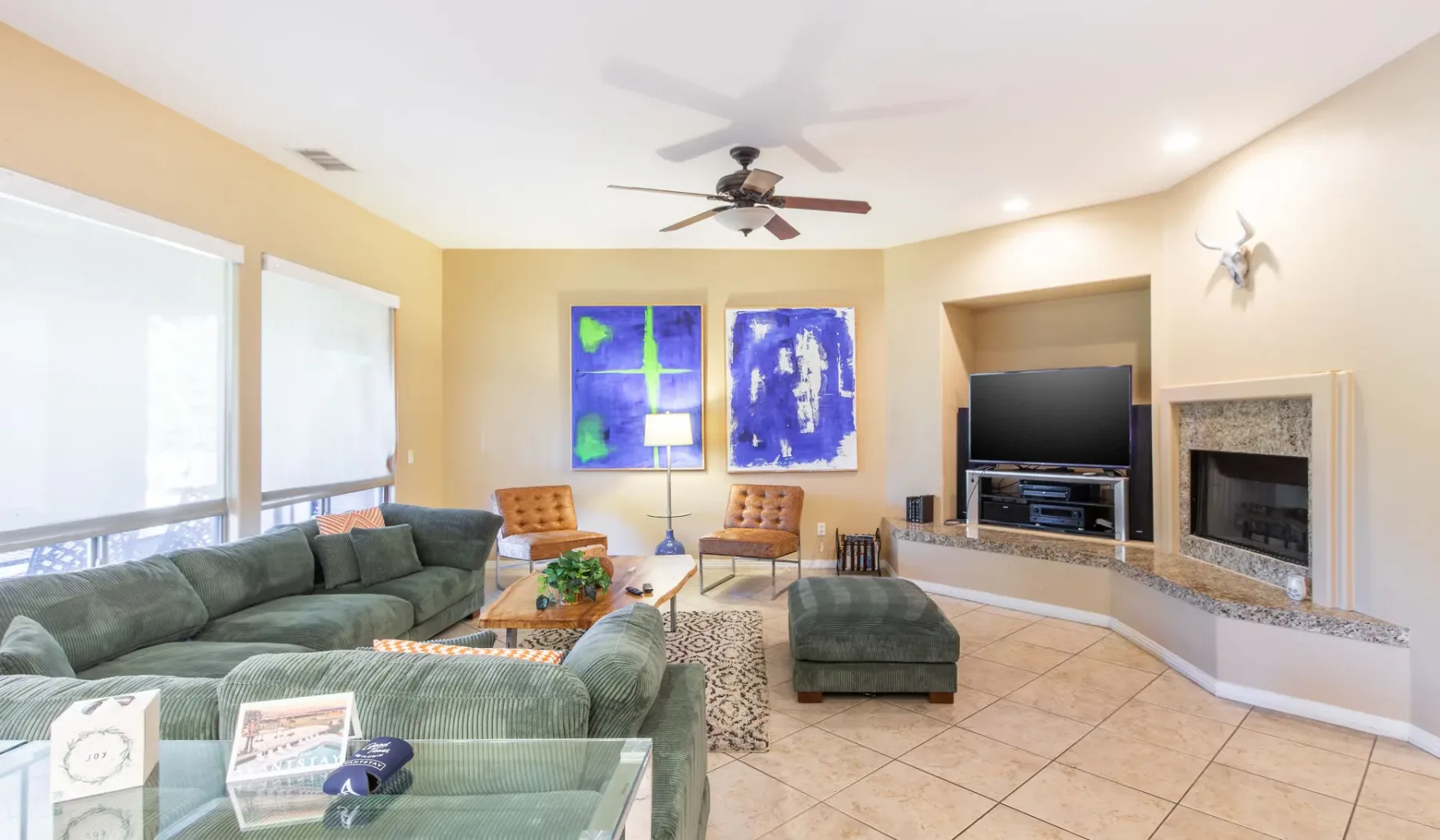 A living room with green seating, a television, and a fireplace.