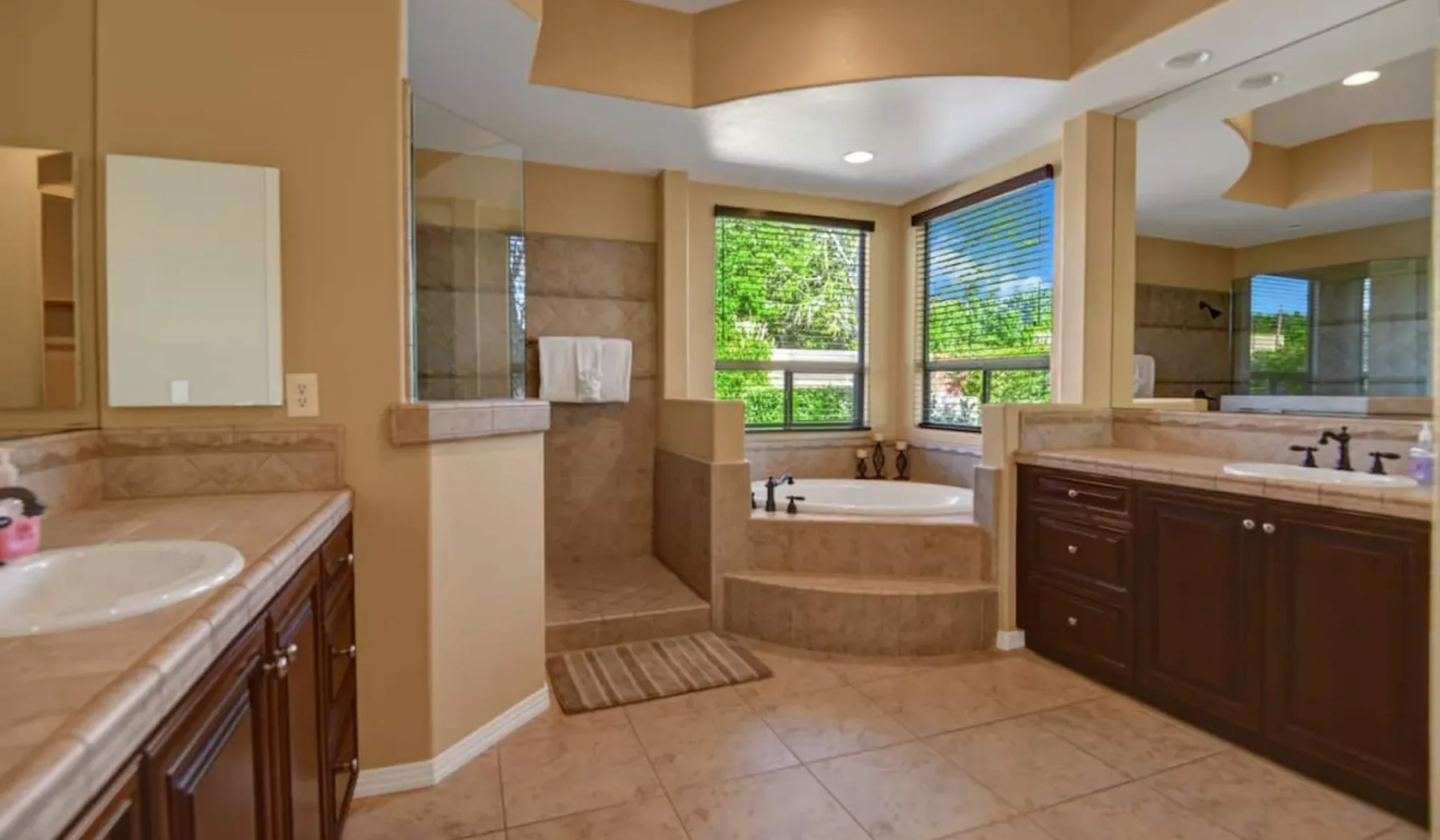 A spacious bathroom with a bathtub, glass shower, and double vanity.