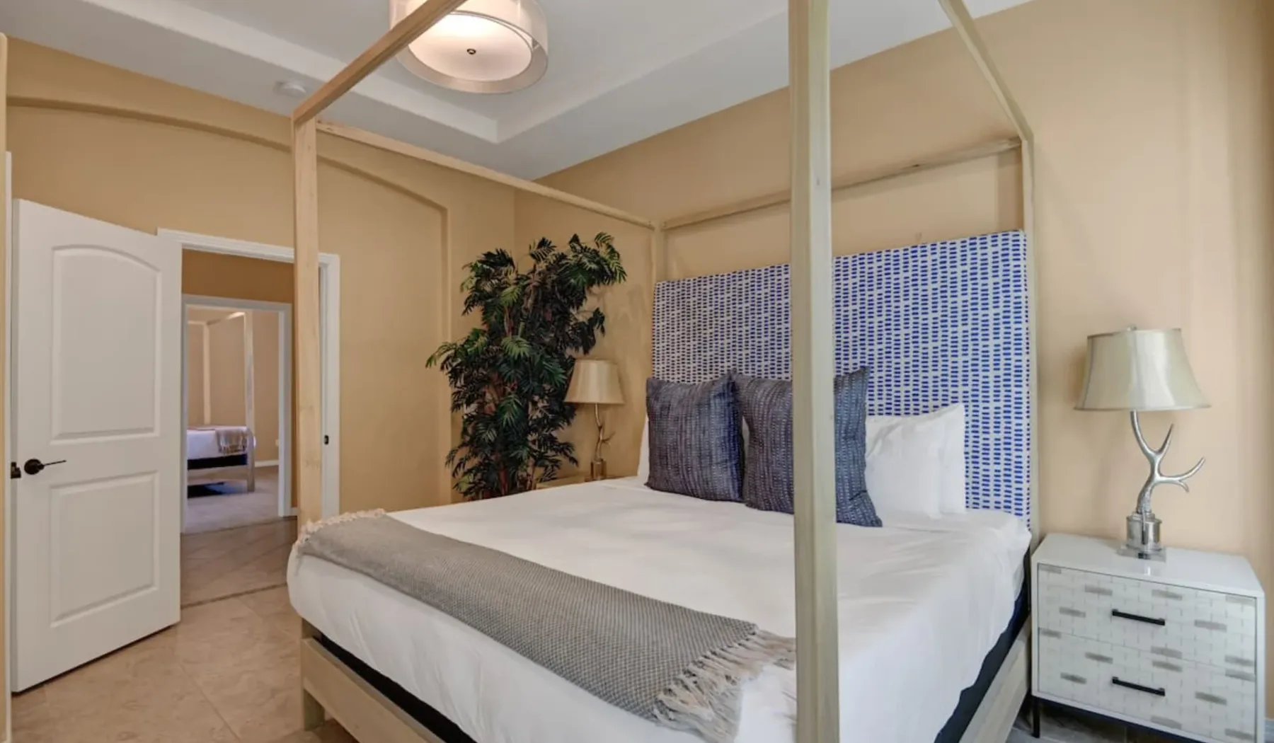 A bedroom with a large bed, patterned wall tiles, and bedside tables.