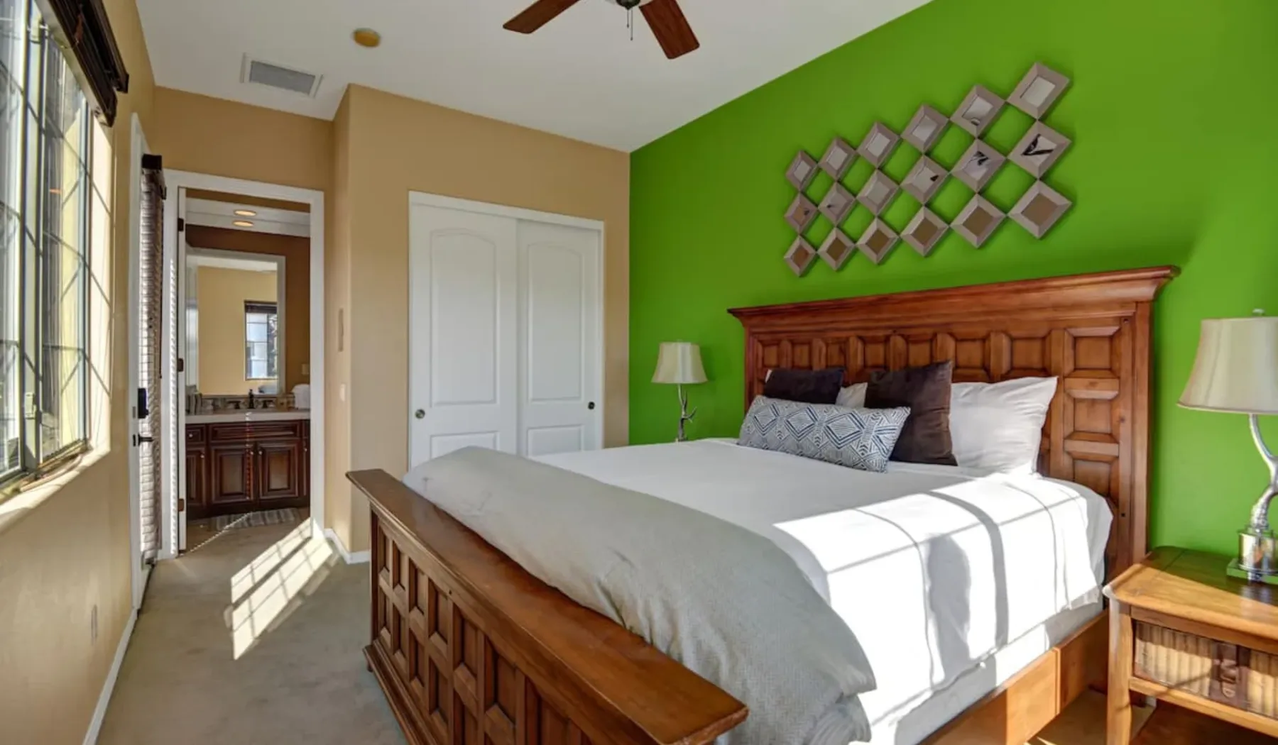 A bedroom with a large bed against a bright green wall.