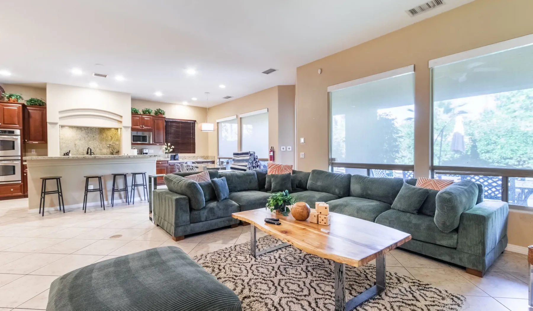 A living room with sectional seating, a coffee table, and large windows.