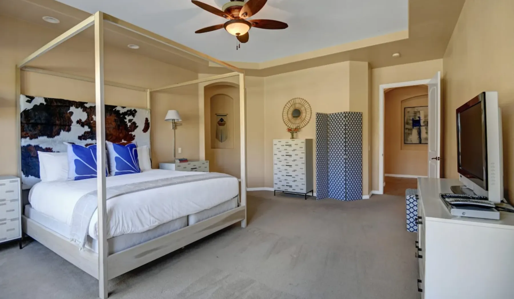 A bedroom with a canopy bed, dresser, and television.