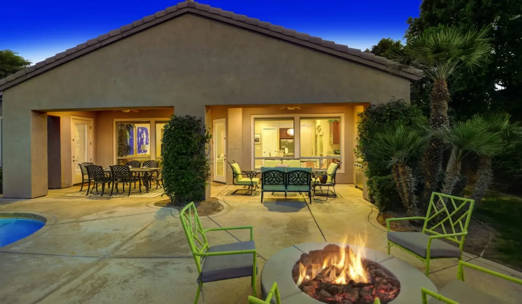 A patio with outdoor seating and a fire pit beside a house.